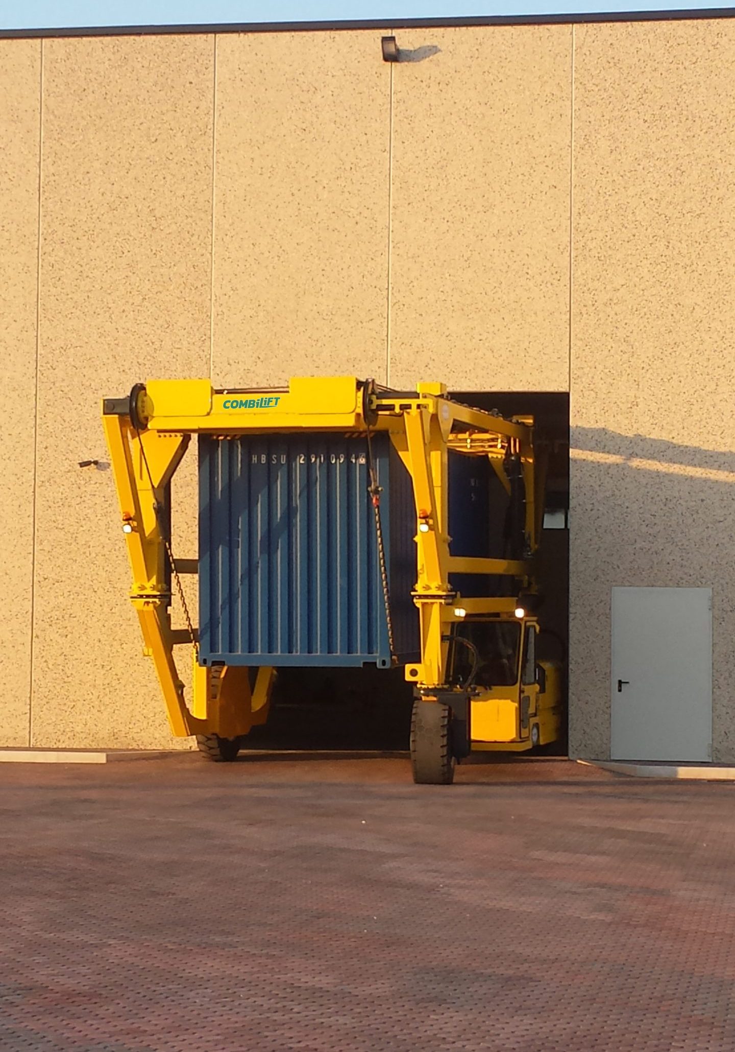 Combilift Telescopic Straddle Carrier lifting containers into a building